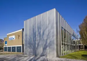 De nieuwbouw is als een apart doosje naast het bestaande bakstenen gebouw gezet