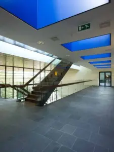 De vierkante kokers van de daklichten op de tweede verdieping zijn helderblauw geschilderd, waardoor ze bijna geen diepte lijken te hebben.