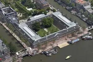 Luchtfoto met op voorgrond de Amstel, duidelijk zichtbaar zijn de glazen daken van de tentoonstellingszalen en het auditorium
