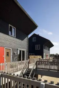 1 De gevels zijn bekleed met zwart gecoat Cape Cod, verwerkt in horizontale, gepotdekselde velden, afgewisseld met verticale delen