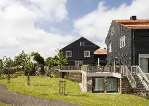 Het open buitenterrein met op de achtergrond de houten schuurtjes behorend bij de gezinswoningen. De appartementen in het basement zijn, indien gewenst, via een trapkast bereikbaar vanuit de bovenliggende woning (mantelzorg). 