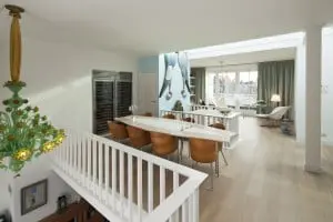 Doorzicht op de bovenverdieping, met van voor- naar achtergevel een vide, de speciaal voor deze plek en bij de Starckstoelen ontworpen eettafel, de trap en een zithoek bij het dakterras