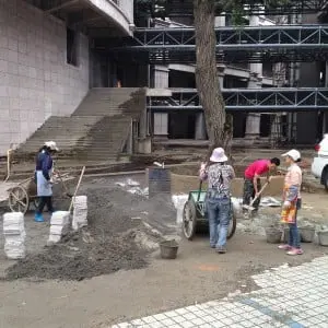 In China werken veel vrouwen in de bouw, hier bestraten ze de ruimte bij een gloednieuw appartementencomplex in Guiyang. Wolbert zit in de architectenselectie voor de restyling van het belendende hotel in neoklassieke stijl, dat aan dit complex gekoppeld wordt.