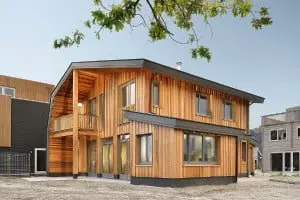 De vrijstaande houten parkwoning in het Homeruskwartier in Almere heeft een houtskelet met een dampopen wandconstructie. Het dak van WRC-houten shingles loopt door tot aan de grond en sluit het huis aan de noordzijde af. Een erker en een balkon aan de zuidkant vergroten uitzicht en beleving richting het park. Foto: Chiel de Nooyer