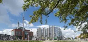 De gevel loopt vanaf het Westplein geleidelijk af richting de Damstraat. Op de voorgrond de nieuwe moskee