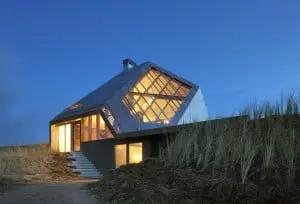 Vanuit het noordwesten, grote vensters zorgen voor een intense beleving van duinen en zee. De gevel met de lichte helling vormt als vanzelf de loungebank op het terras
