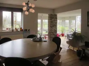 Zicht vanuit de eetkeuken richting
serre met zithoek van de woning. De vloerdelen
hebben een derde leven: oorspronkelijk toegepast
in treincoupés zijn ze via een andere boerderij in
dit woonhuis terecht gekomen.