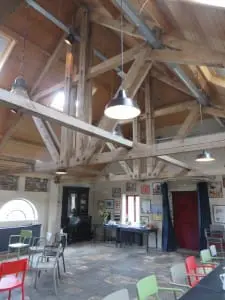 De zaal met verhoogde kap en verlaagde
vloer, met hergebruik van oude spanten en
tegels en klinkers. Boven de stalvensters is de
oorspronkelijke hoogte zichtbaar