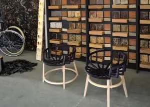 Tulipa, een houten  kuipstoel gepoedercoat met tulppigment in een dieppaarse kleur. Links de Carbon Strandbike en achter een  bibliotheek van biolaminaten