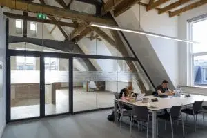 De zolder van de statenvleugel met studieplekken. Door de glazen wand met Jansen-profielen is het
stalen spant boven de grote trap zichtbaar. Op diverse glaswanden in het gebouw heeft Karin van Pinxteren een patroon aangebracht, gebaseerd op sleutelstukken en het motto van de universiteit.
