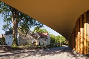 Door de gebogen dakvorm lijkt het paviljoen de oude hoeve te omarmen. Foto Mecanoo.