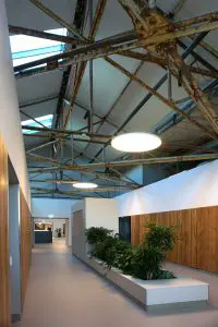 Middengang. Installaties zijn weggewerkt achter houten panelen. Tussen twee woningentrees is een blauw paneel met pinnen, waaraan bewoners persoonlijke dingen kunnen ophangen. 