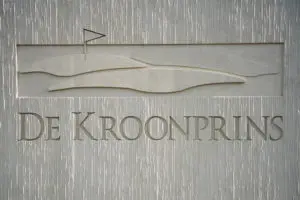 Door de verspringende reliëfdiepte wordt het in de betontextuur verwerkte logo van de golfbaan benadrukt 