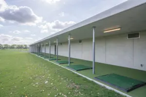 De natuurlijke uitstraling van het beton door afwerking met een structuur, wordt doorgezet in de driving range waarvan de wanden in het werk gestort zijn