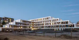 Door te kiezen voor een omarmend gebouw bleef de open plek behouden voor de buurt. Het aftrappen van de gevel zorgt voor maximale bezonning en vergroot het toezicht vanuit de omringende woningbouw