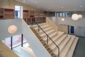 Een houten tribune dient als leeszaal voor de bibliotheek op de verdieping. Bij voorstellingen gaan aan de voet van de trap grote deuren open naar de multifunctionele ruimte.