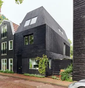 De gevel en het hellende dak van de woning zijn bekleed met zwart gebrand hout. Een verwijzing naar de waterlandstijl