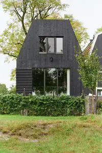 De achterkant van de woning grenst aan een klein talud met toegang tot een aangrenzend park. De raampartijen achter zijn van een groot formaat