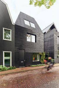 De gevel en het hellende dak van de woning zijn bekleed met zwart gebrand hout. Een verwijzing naar de waterlandstijl